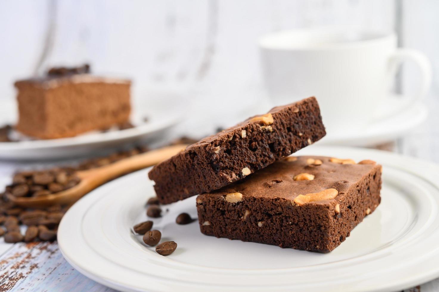 Chocolate brownies on a white plate and coffee beans on a wooden spoon photo