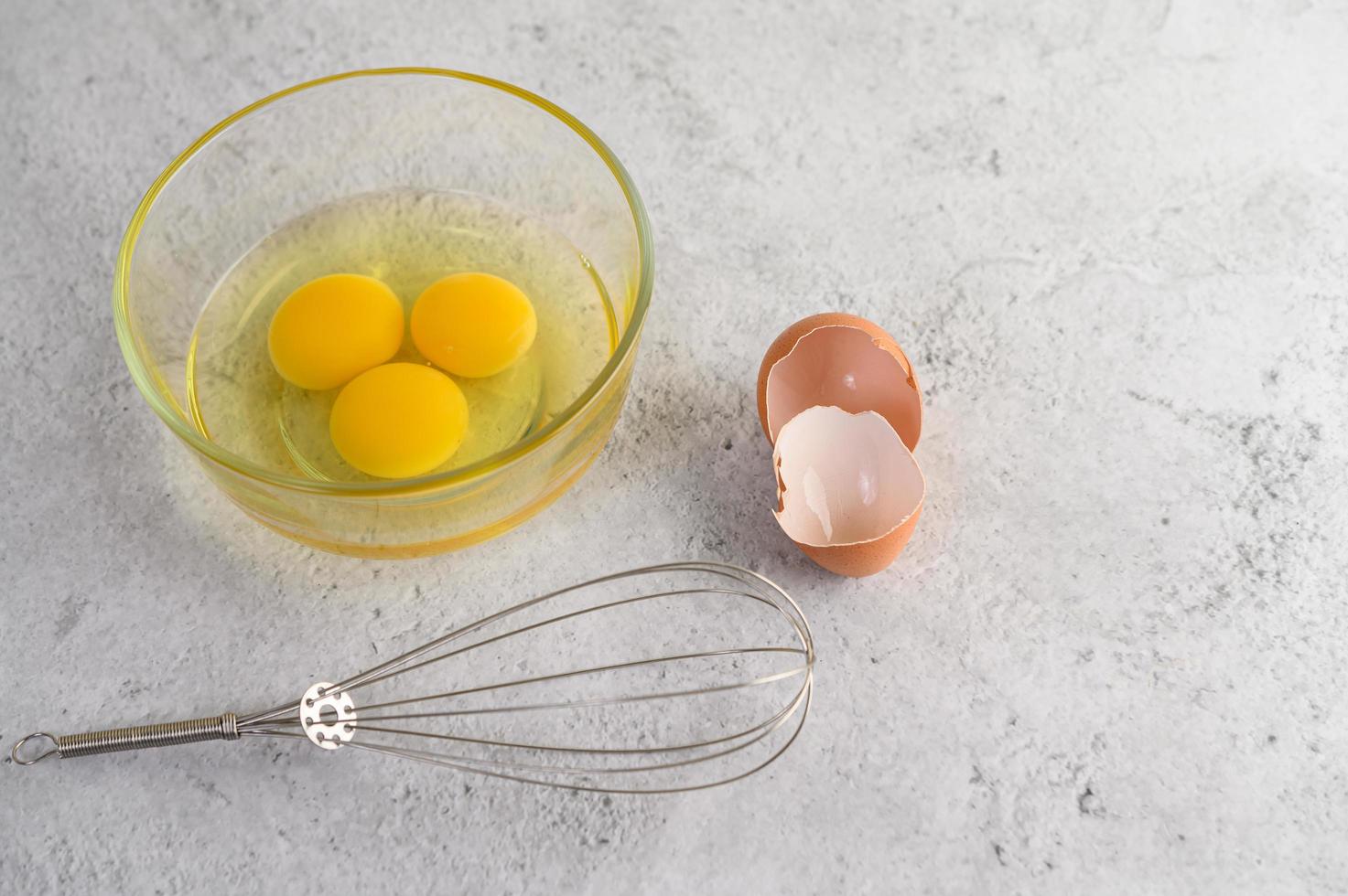 Egg yolks in a glass bowl with shell and whisk photo