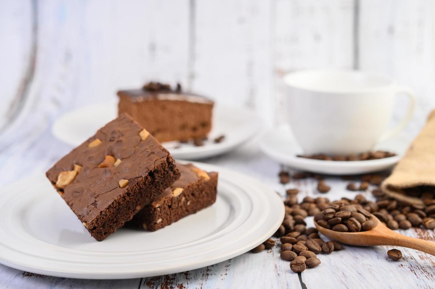 Brownies de chocolate en una placa blanca y granos de café en una cuchara de madera foto