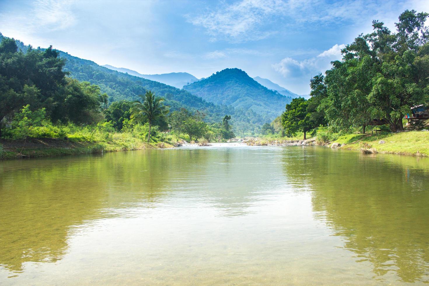 río, bosque y montañas con cielo azul nublado foto