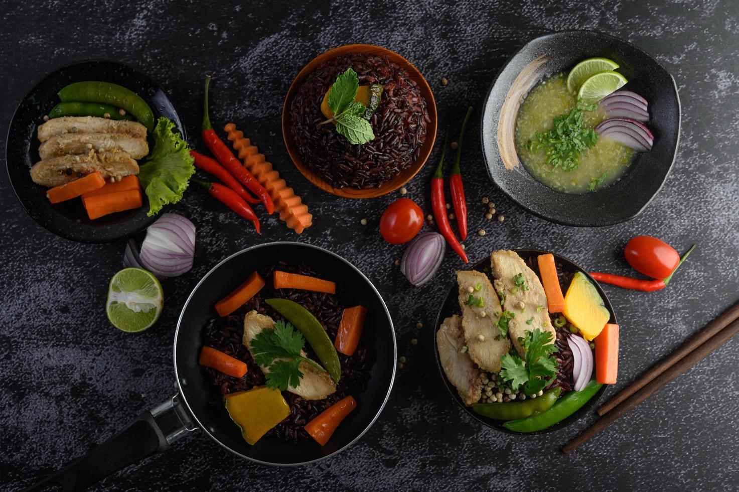 Assorted dishes of vegetables, meat and fish on a black stone background photo