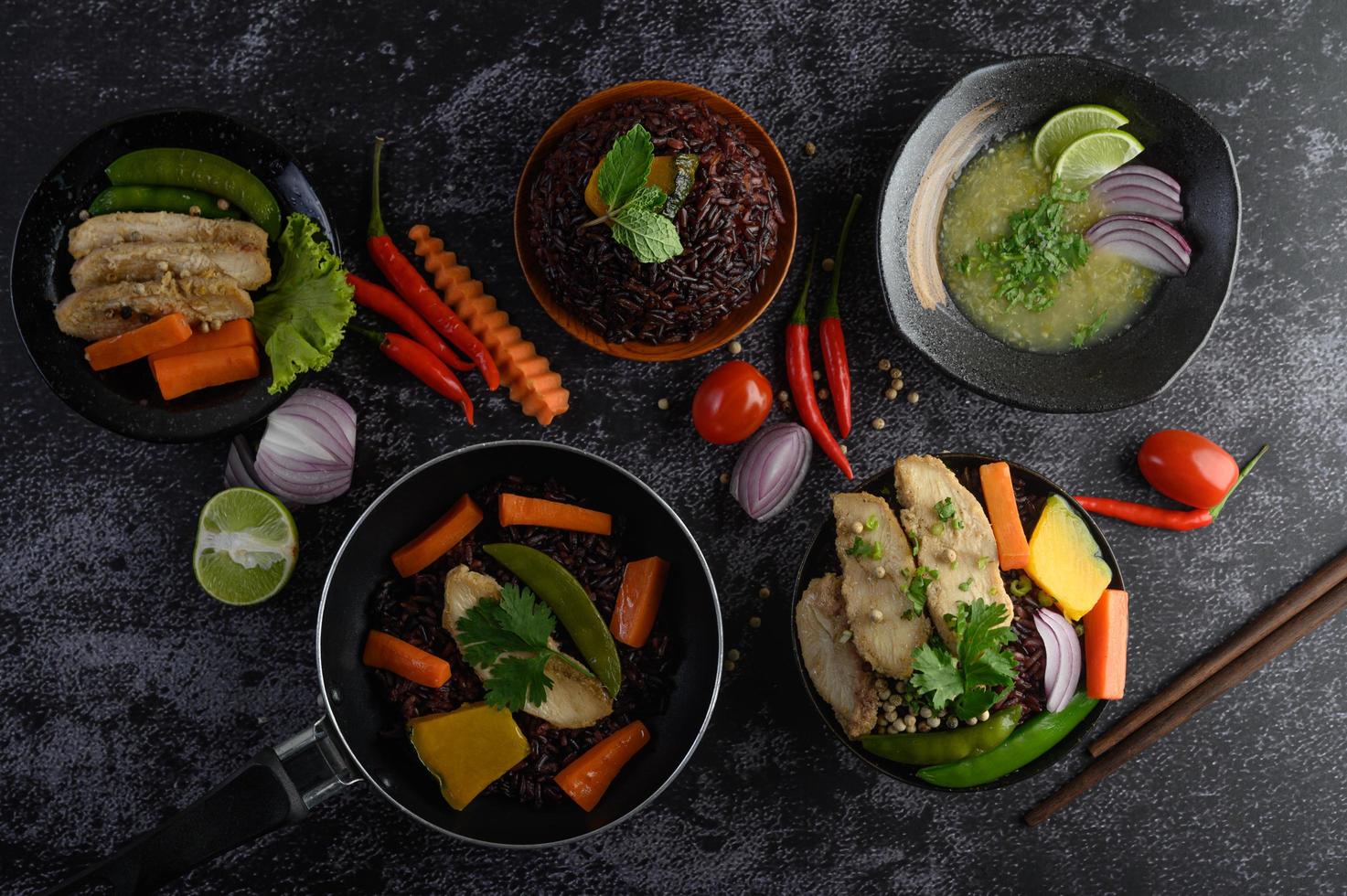 Platos variados de verduras, carnes y pescados sobre un fondo de piedra negra foto