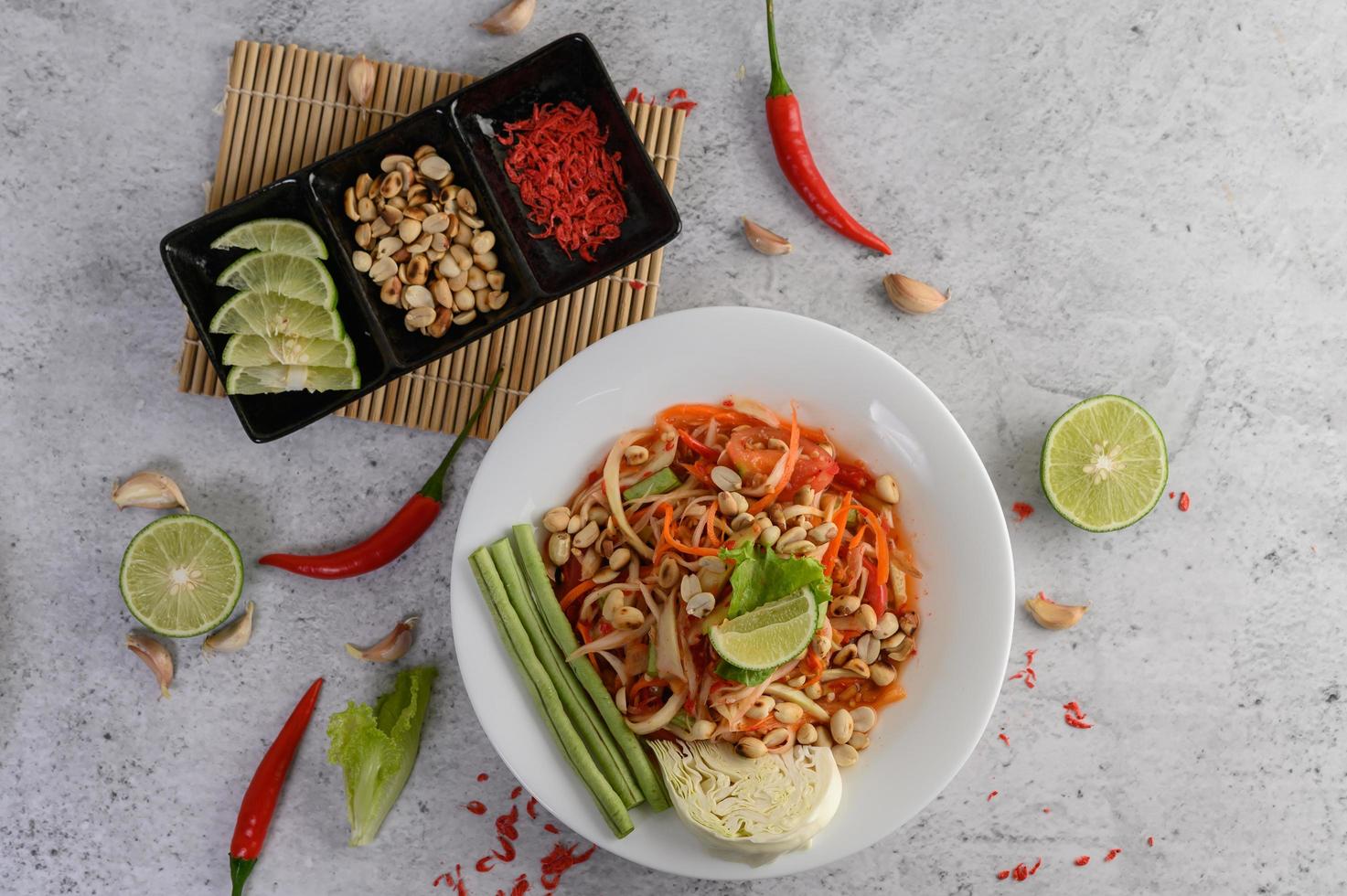 Ensalada de papaya tailandesa en un plato blanco con camarones secos foto