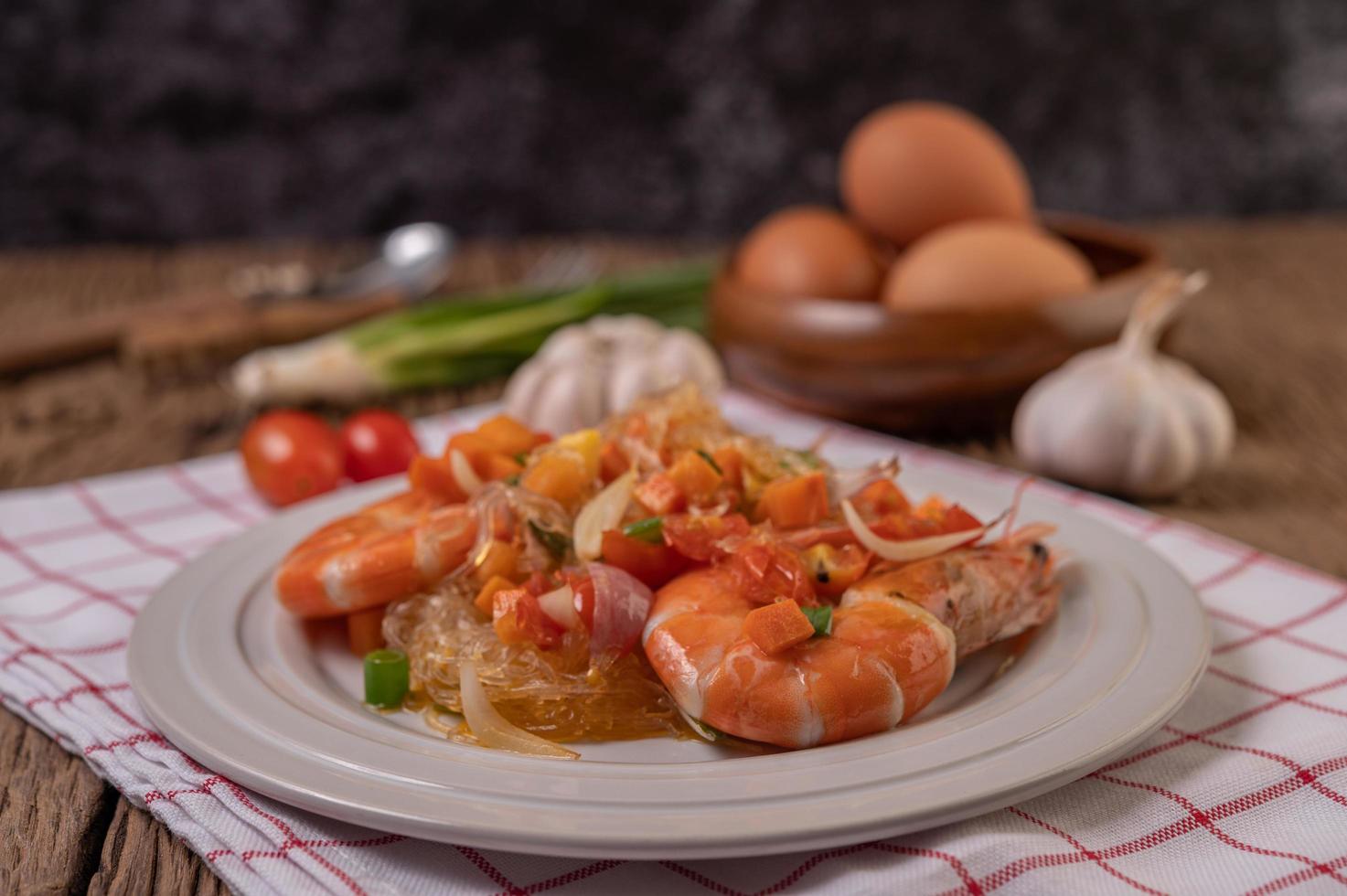 Langostinos salteados con fideos de vidrio sobre un paño rojo y blanco foto