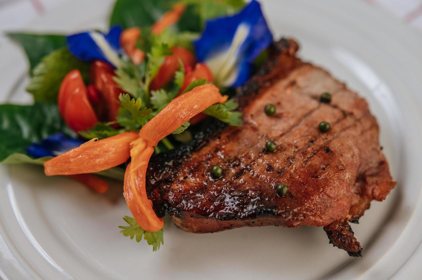 Pork steak with tomato, carrot, red onion, peppermint, butterfly pea flower and lime photo