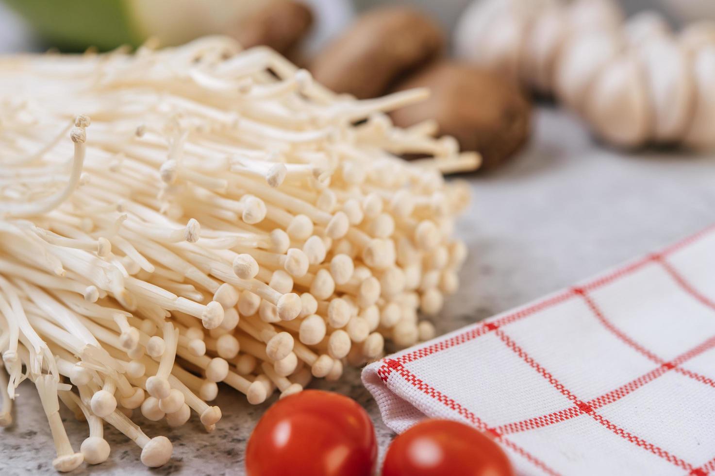 Enokitake and tomato near a red and white cloth photo