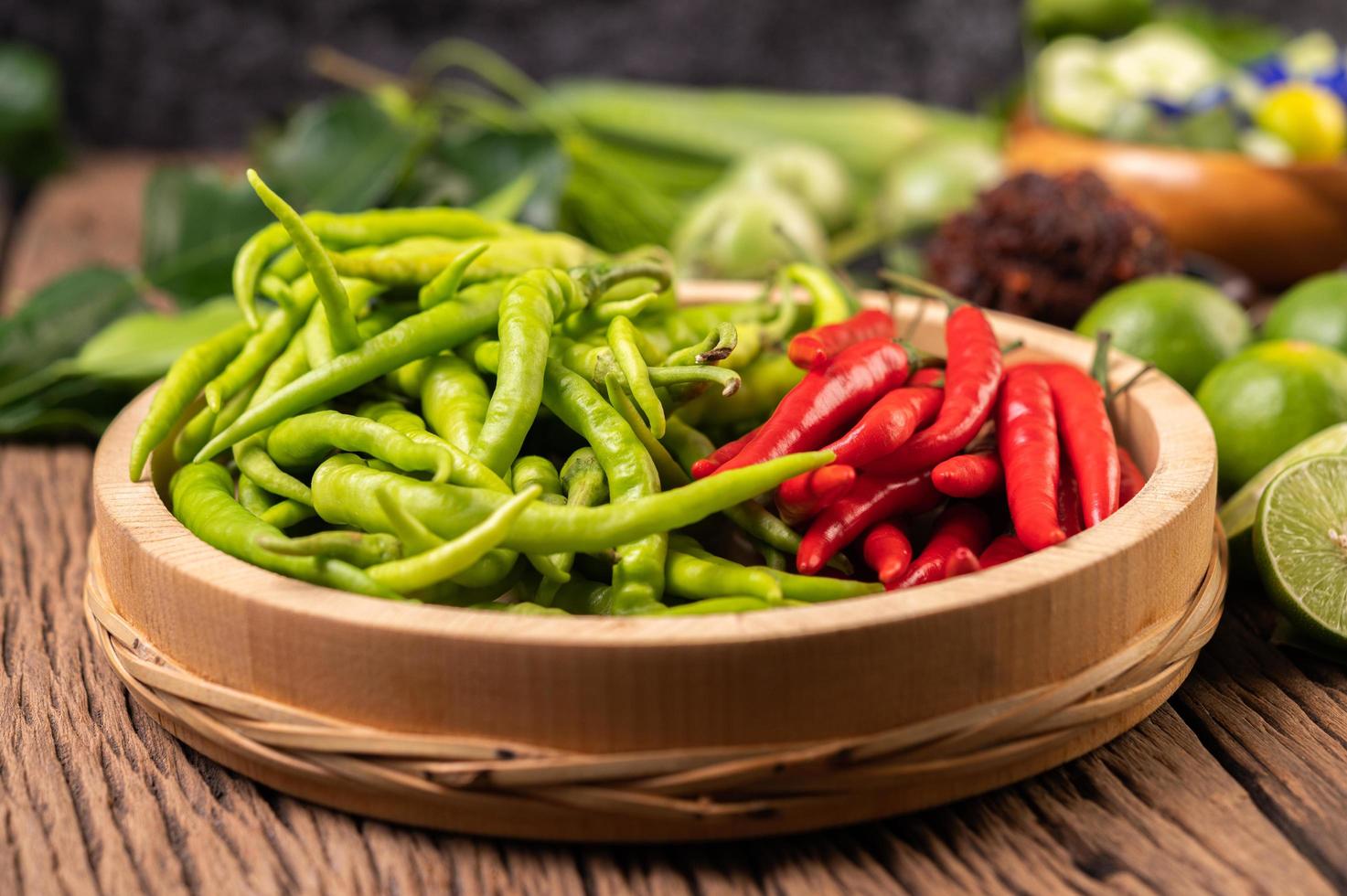 Fresh chili on a wooden tray with lemon and kaffir lime photo