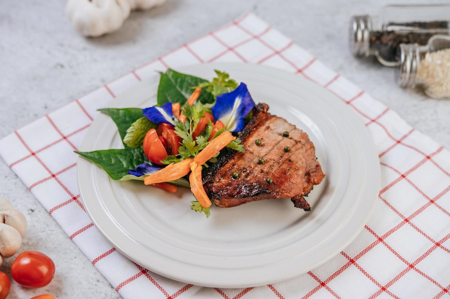 Pork steak with tomato, carrot, red onion, peppermint, butterfly pea flower and lime photo