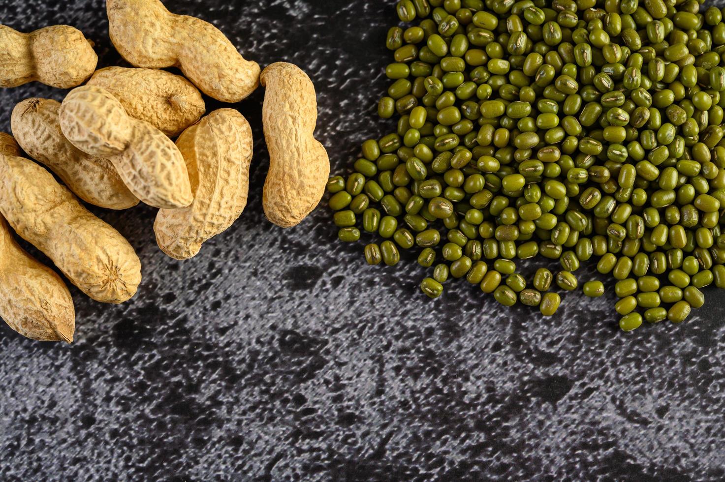 Peanuts and mung beans on a black cement floor background photo