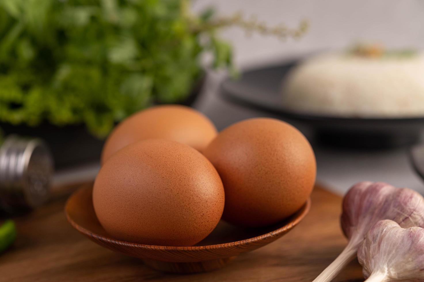 Tres huevos de gallina en un plato con ajo foto