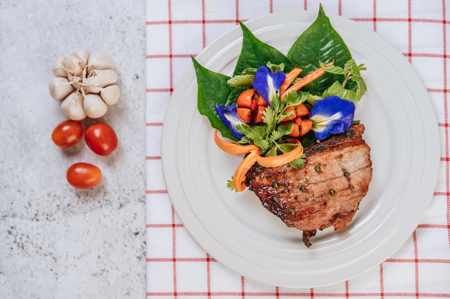 Pork steak with tomato, carrot, red onion, peppermint, butterfly pea flower and lime photo