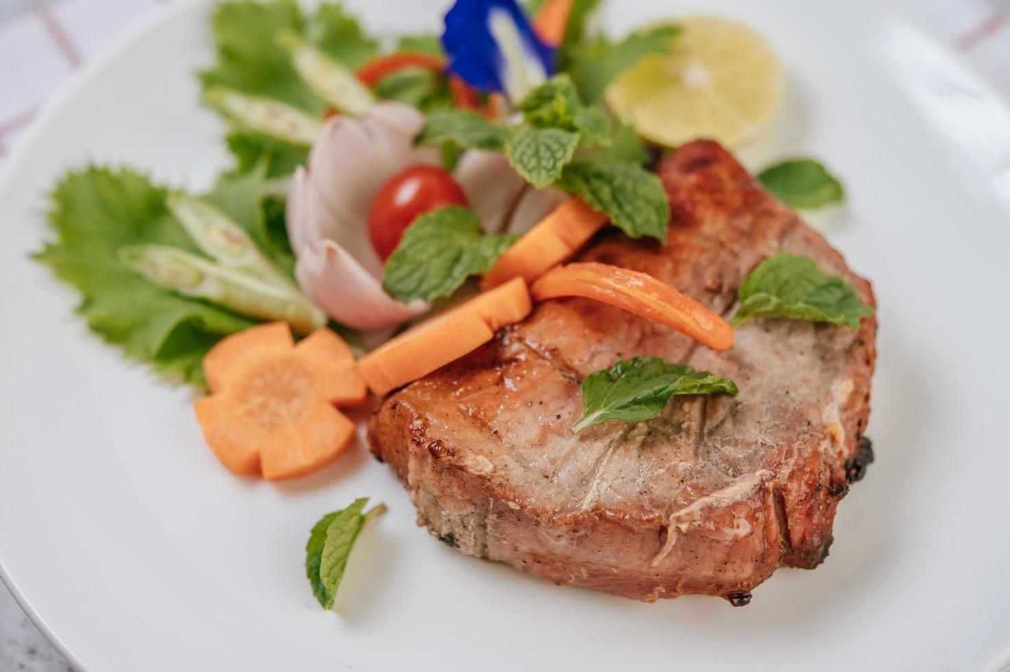 Pork steak with tomato, carrot, red onion, peppermint, butterfly pea flower and lime photo