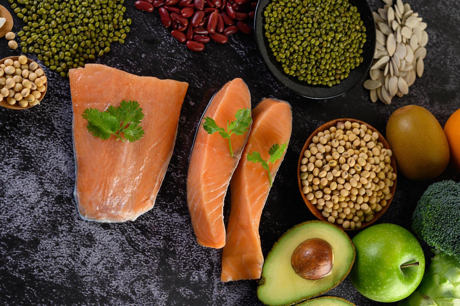 Legumes, fruit, and salmon on a black cement background photo