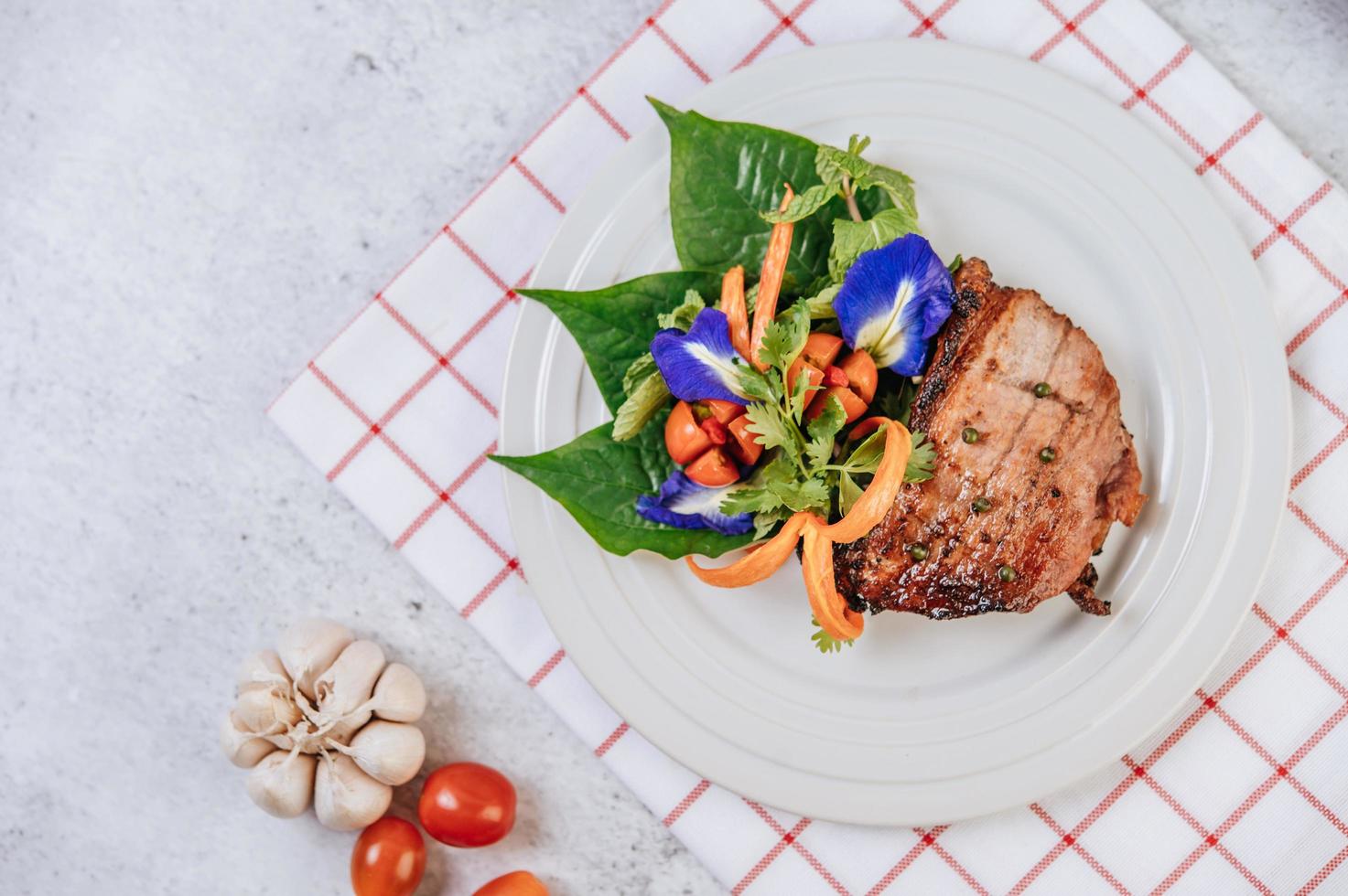 Pork steak with tomato, carrot, red onion, peppermint, butterfly pea flower and lime photo