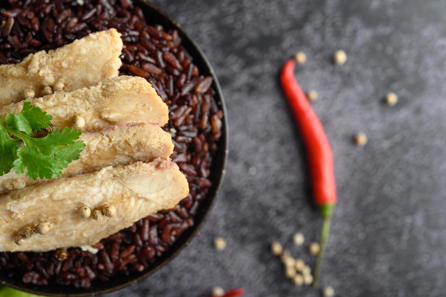 Pechuga de pollo a la parrilla con pimientos sobre bayas maduras de arroz púrpura foto