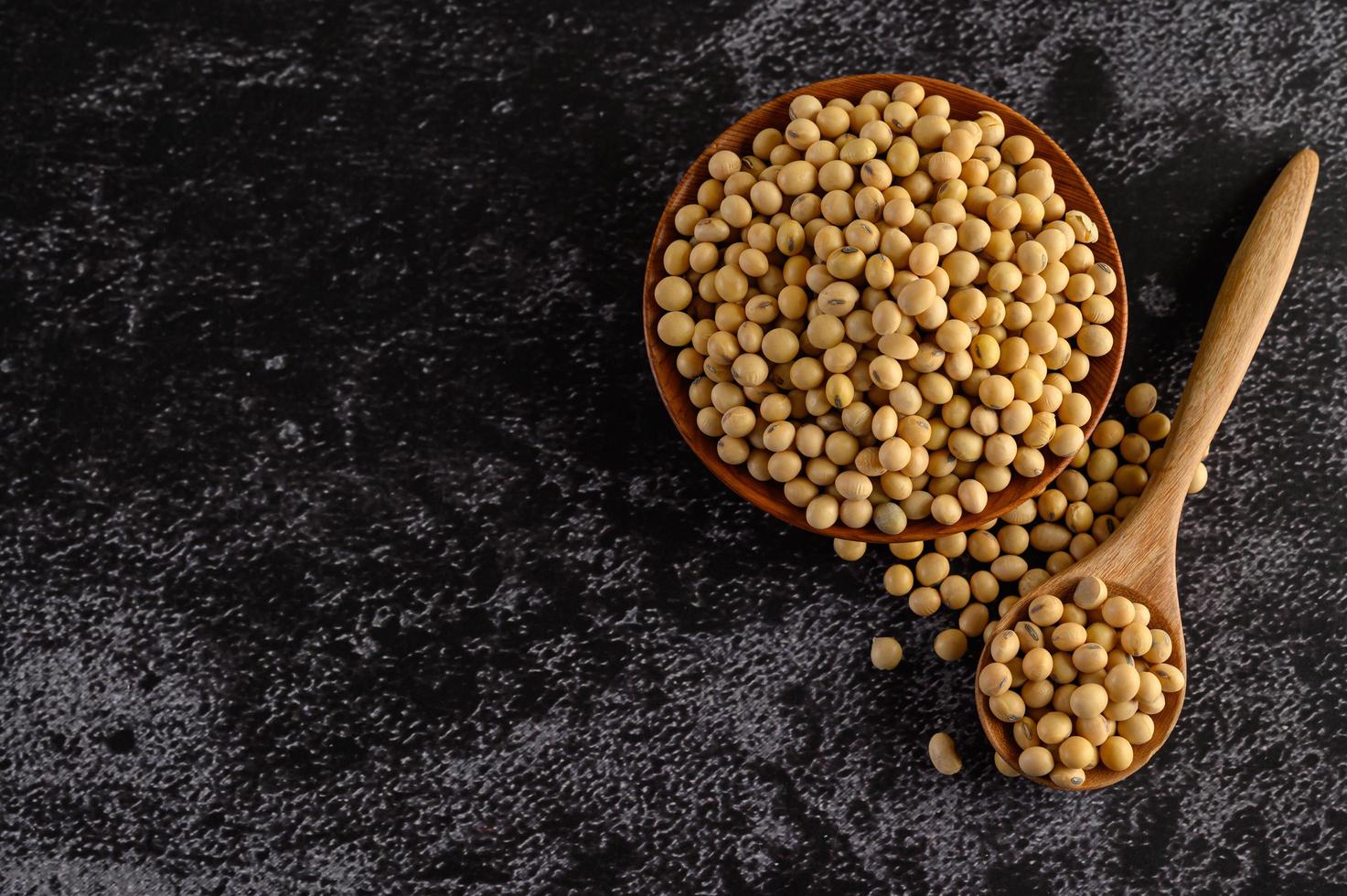 Frijoles amarillos en un cuenco de madera sobre fondo negro foto