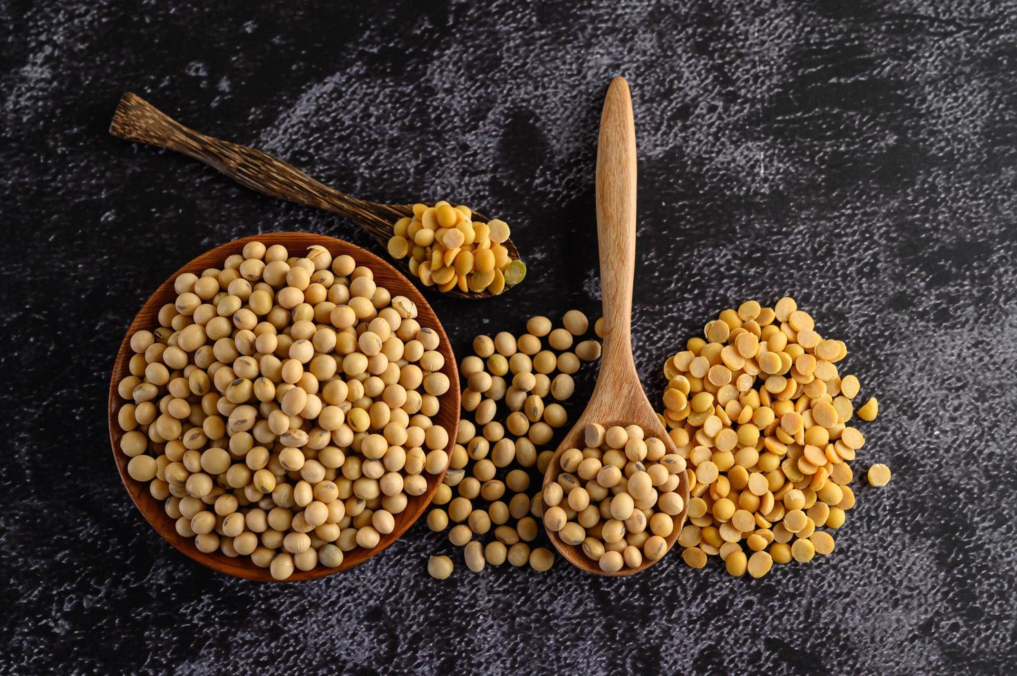 Frijoles amarillos en un cuenco de madera sobre fondo negro foto