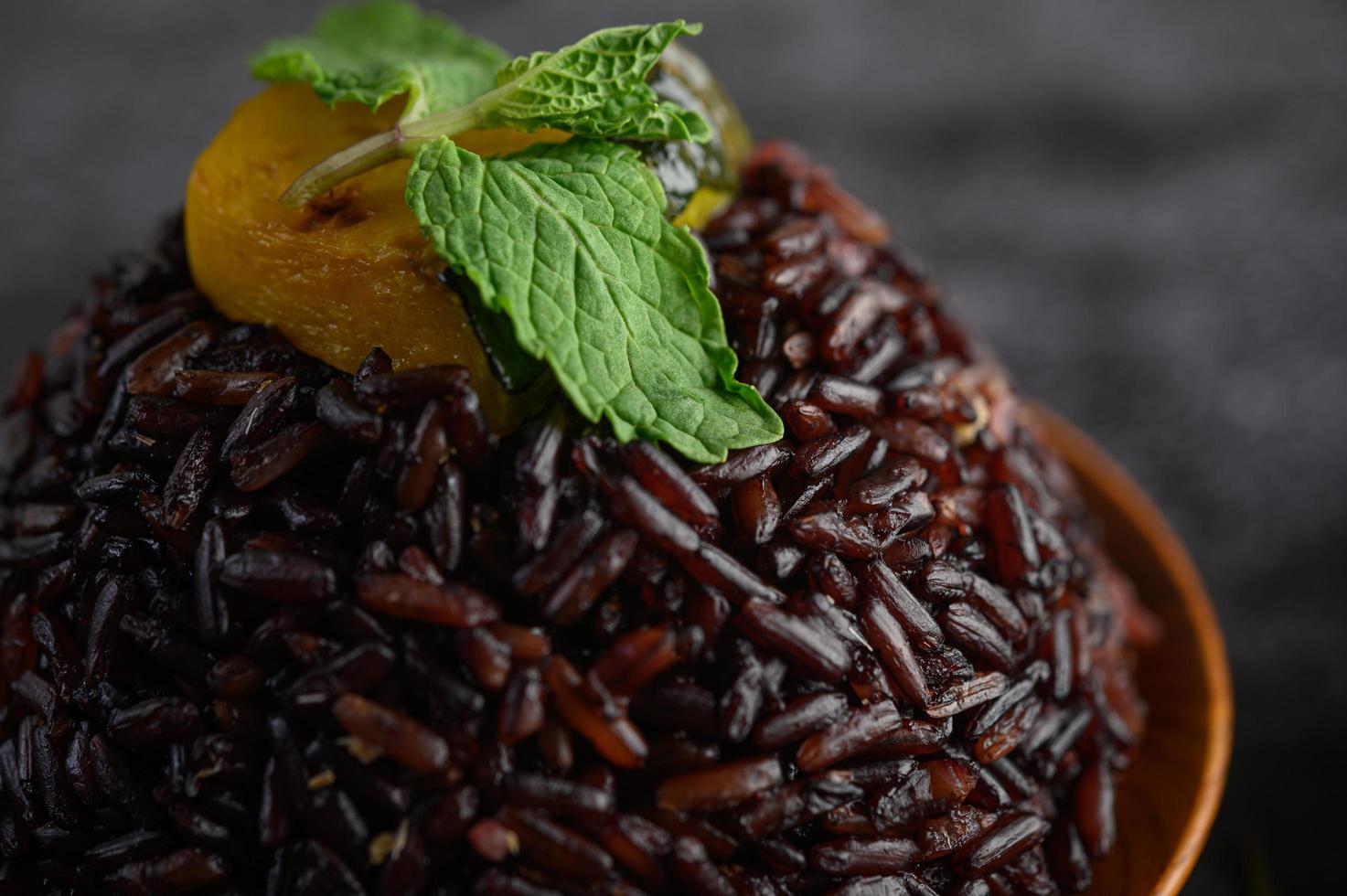 bayas de arroz morado cocidas en un plato de madera con hojas de menta y calabaza foto