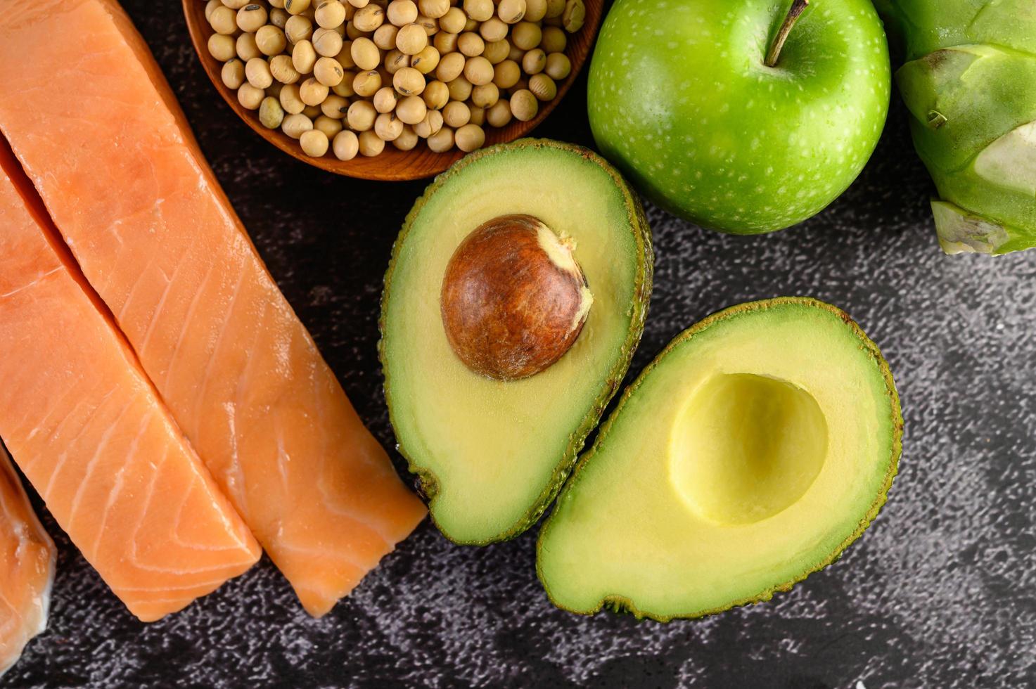 Legumes, fruit, and salmon on a black cement background photo