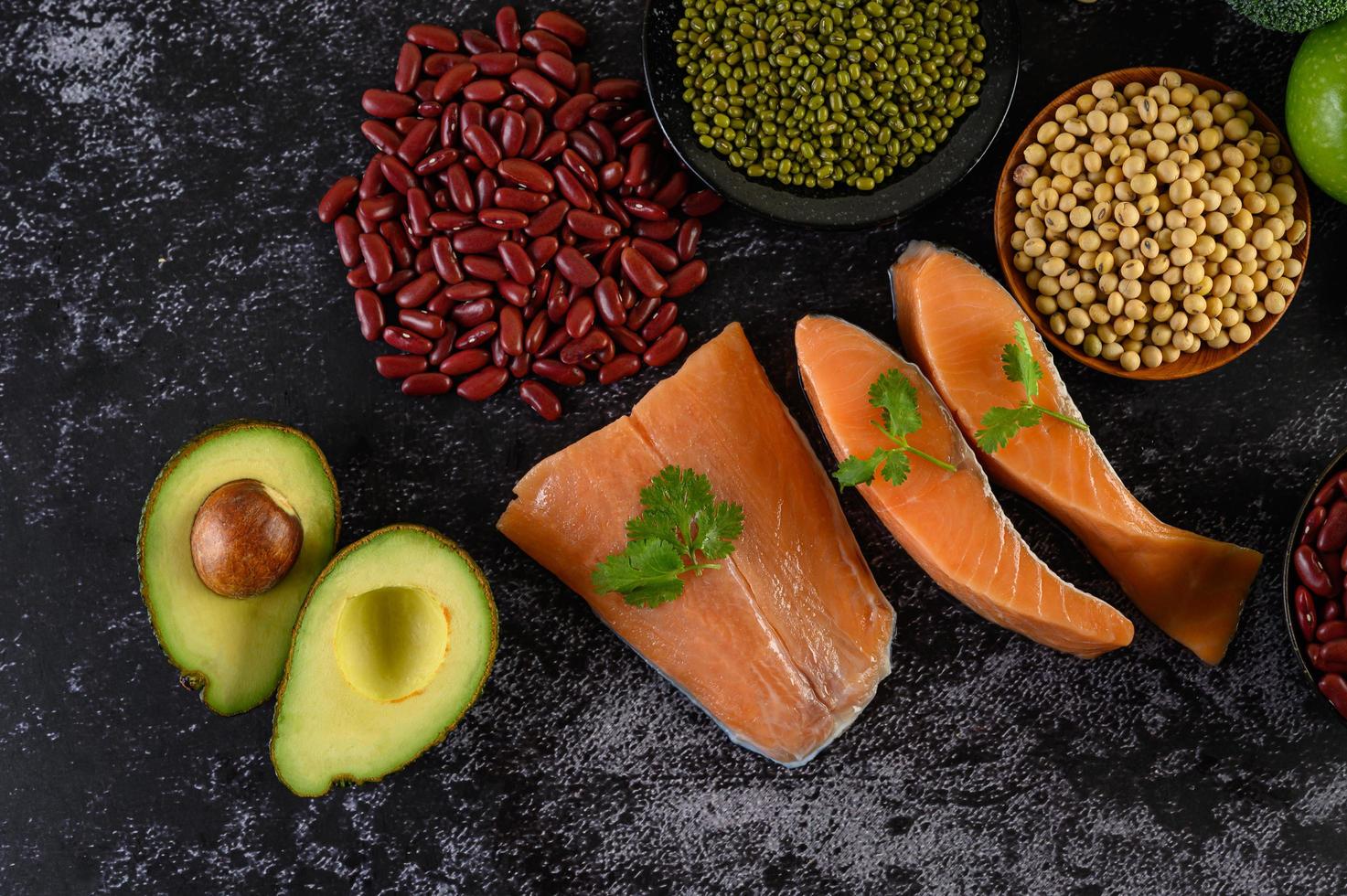 Legumes, fruit, and salmon on a black cement background photo