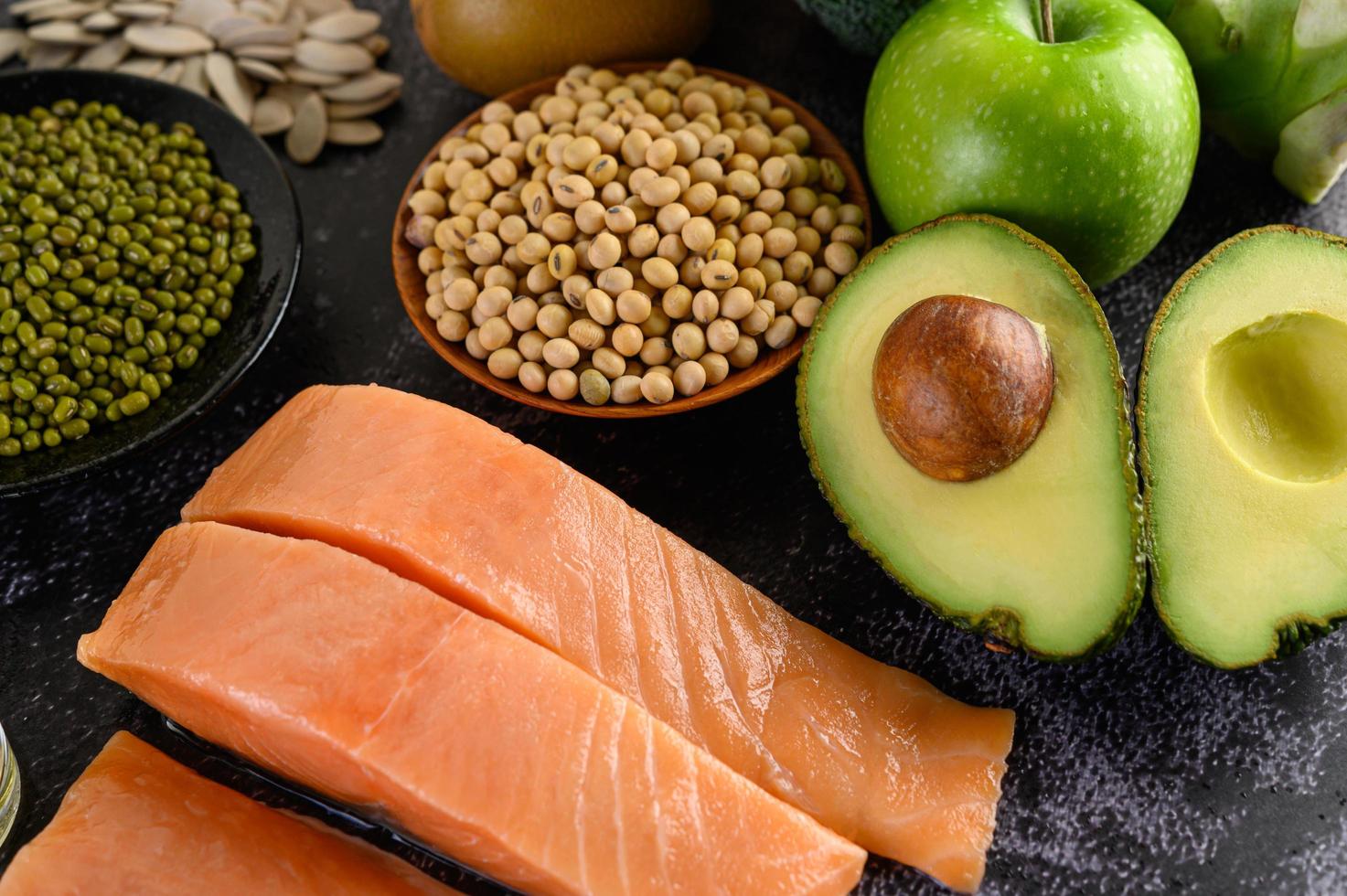Legumes, fruit, and salmon on a black cement background photo