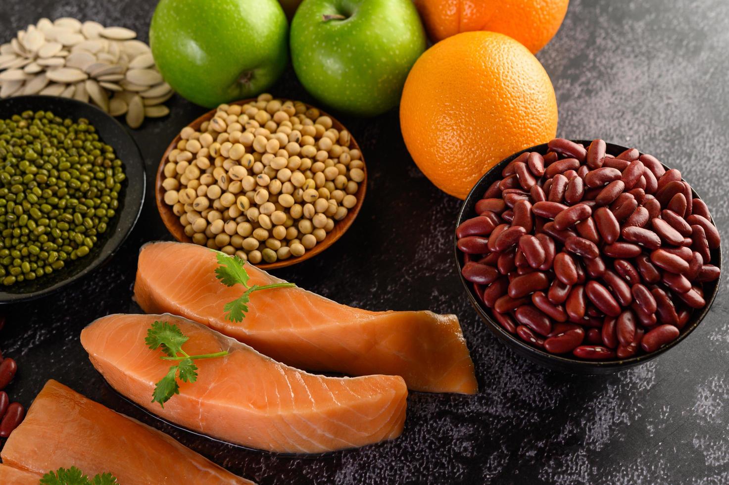 Legumes, fruit, and salmon on a black cement background photo