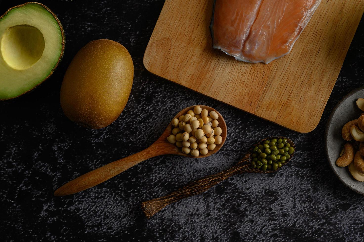 Legumes, fruit, and salmon on a black cement background photo