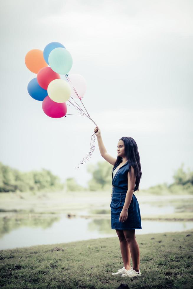 Young woman holding colorful balloons in nature photo