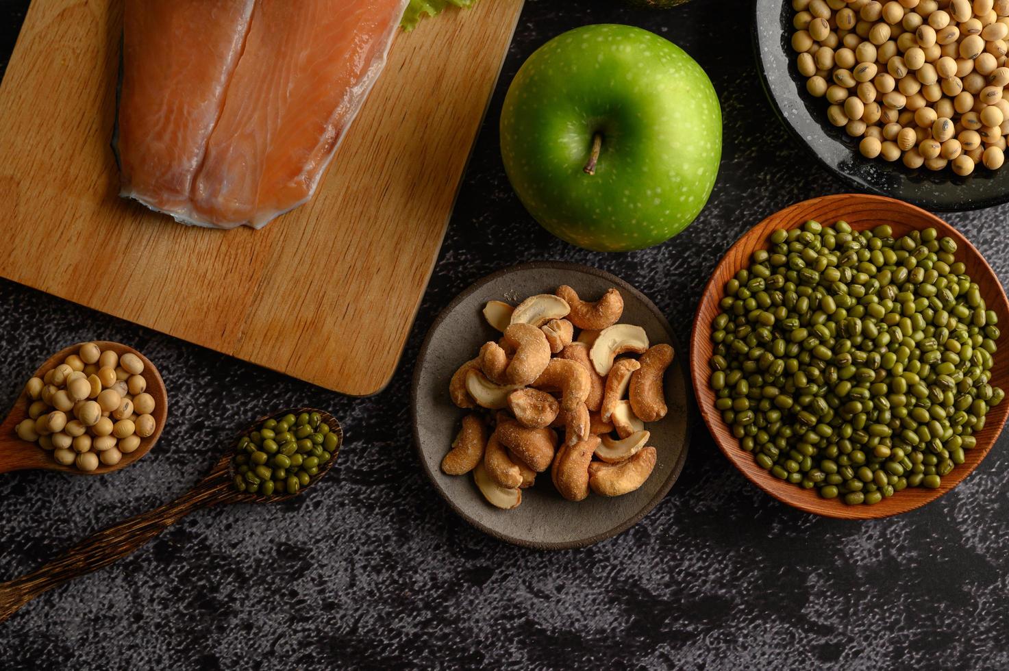 Legumes, fruit, and salmon on a black cement background photo