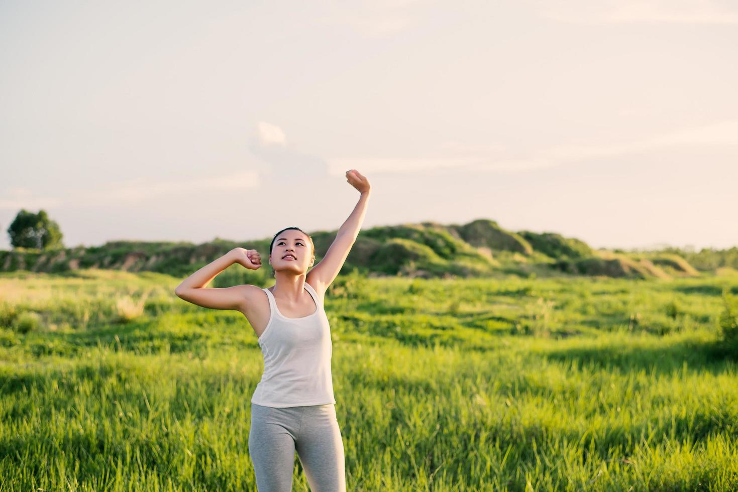 Feliz hermosa mujer con los brazos estirados en una pradera foto