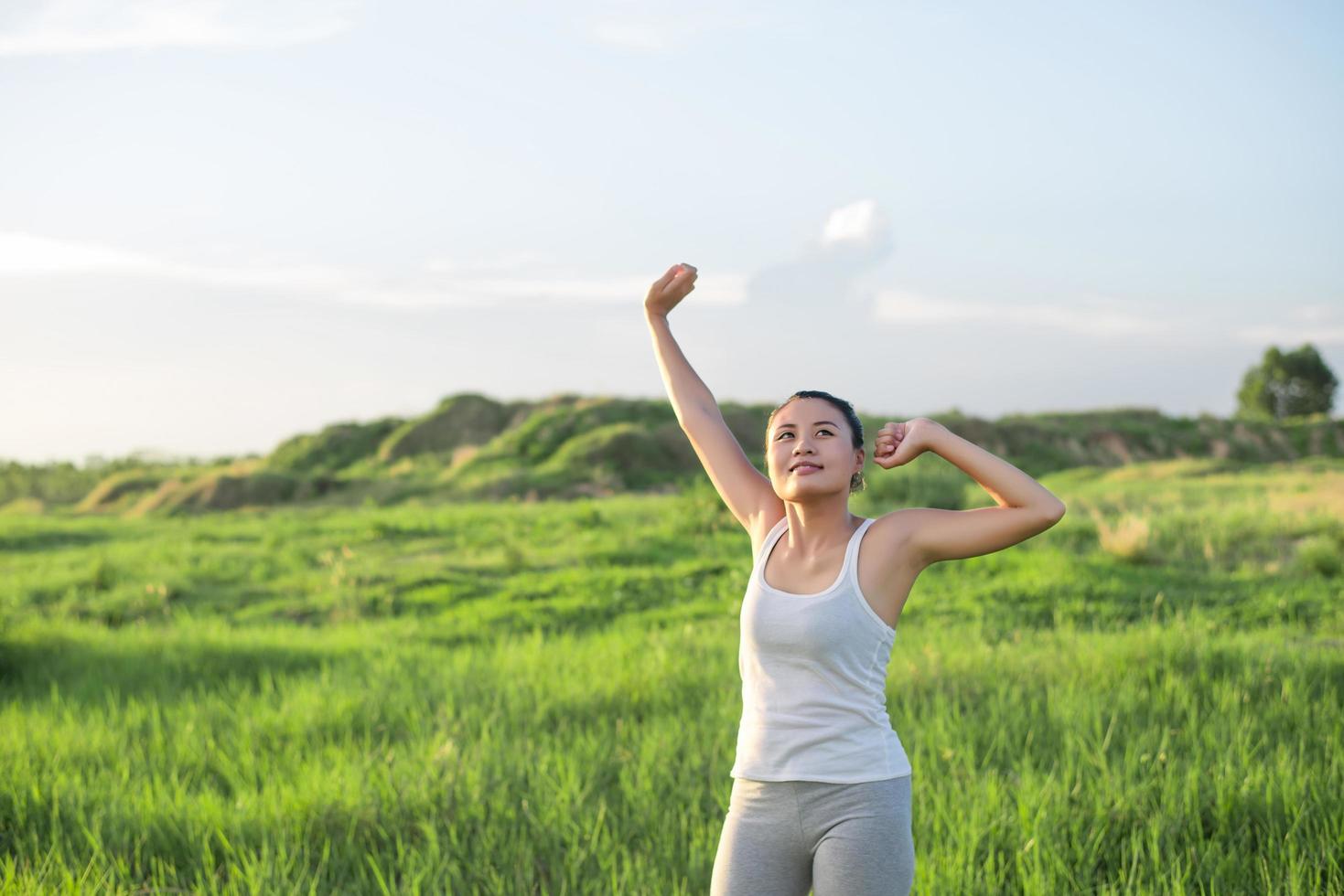 Young beautiful woman raises arms in the fresh air in green meadows photo