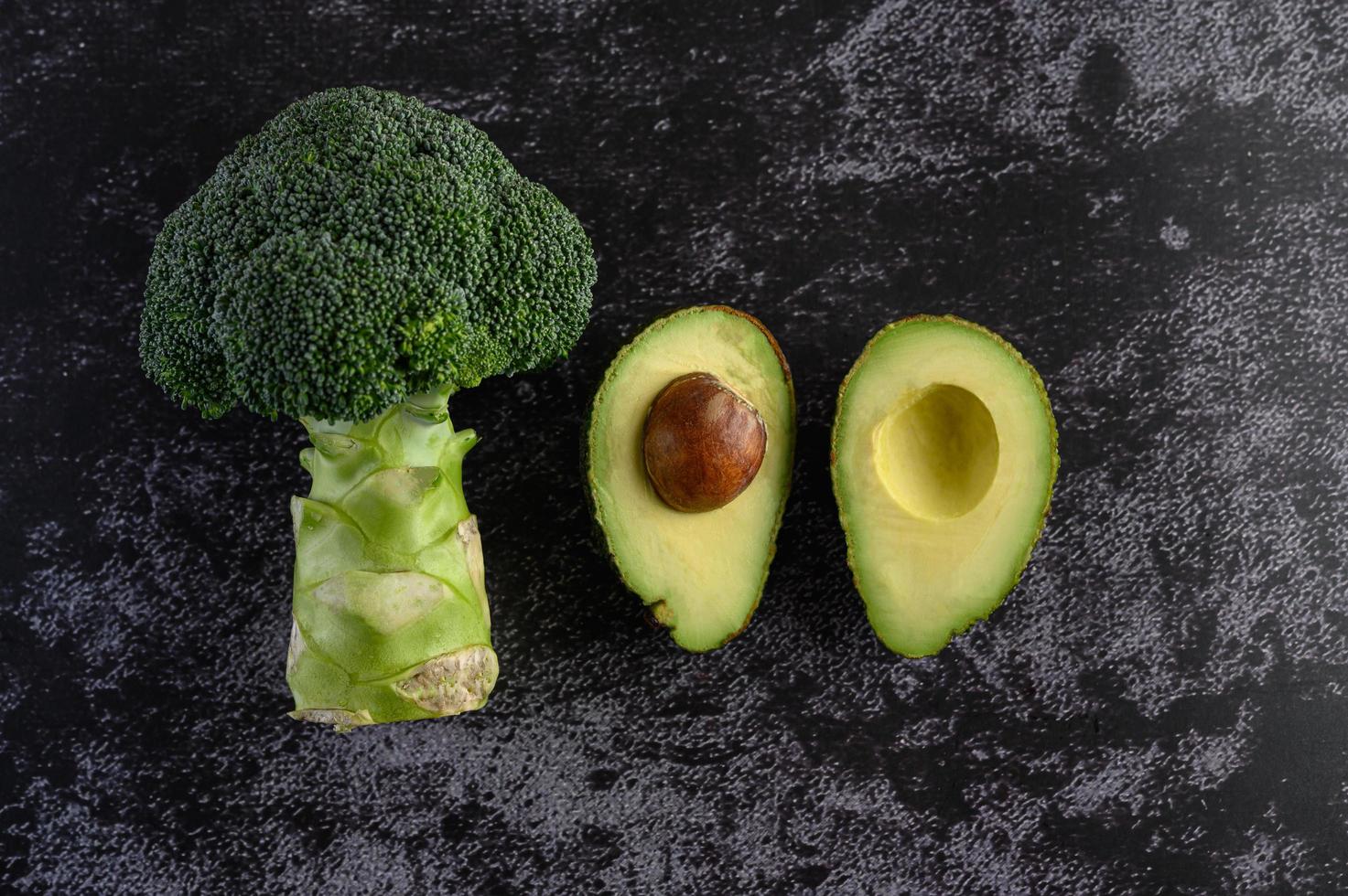 Brócoli y aguacate sobre fondo de piso de cemento negro foto