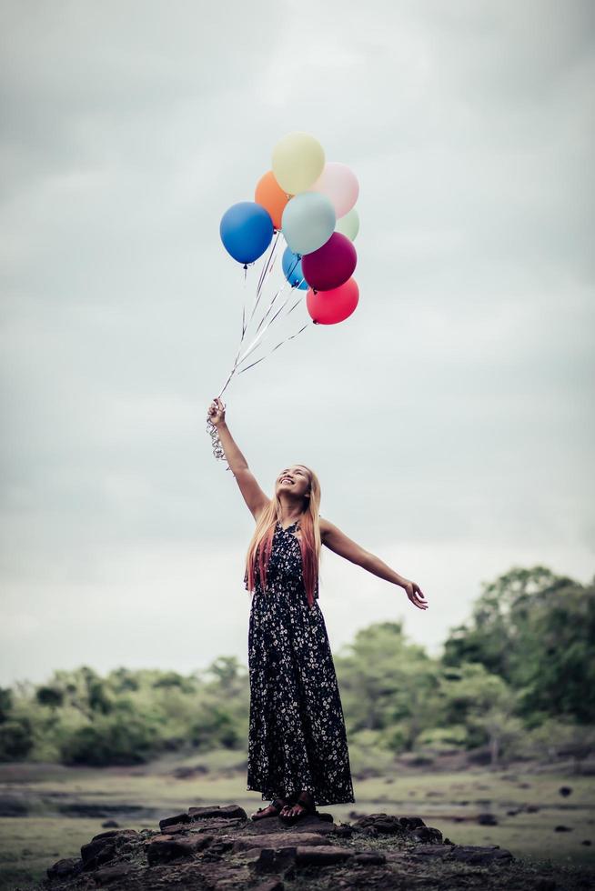 Young woman holding colorful balloons in nature photo