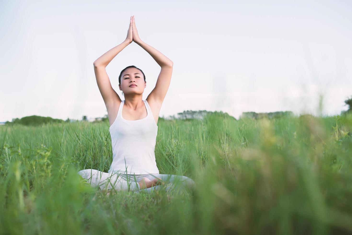 Mujer joven en pose de yoga practicando meditación en los prados foto