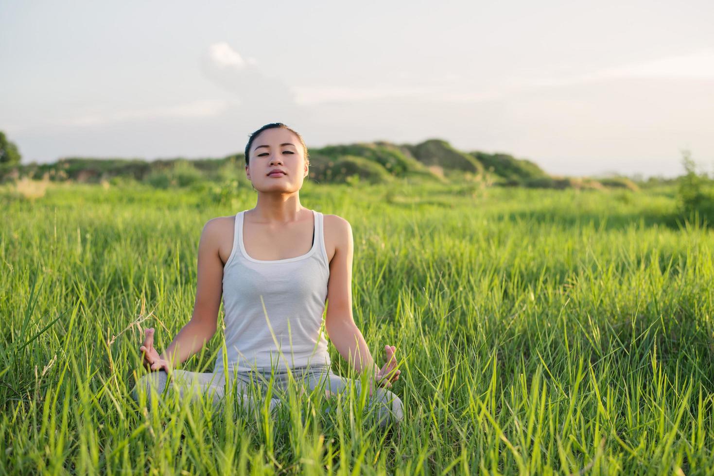 Mujer de yoga en la postura del loto en un prado soleado foto