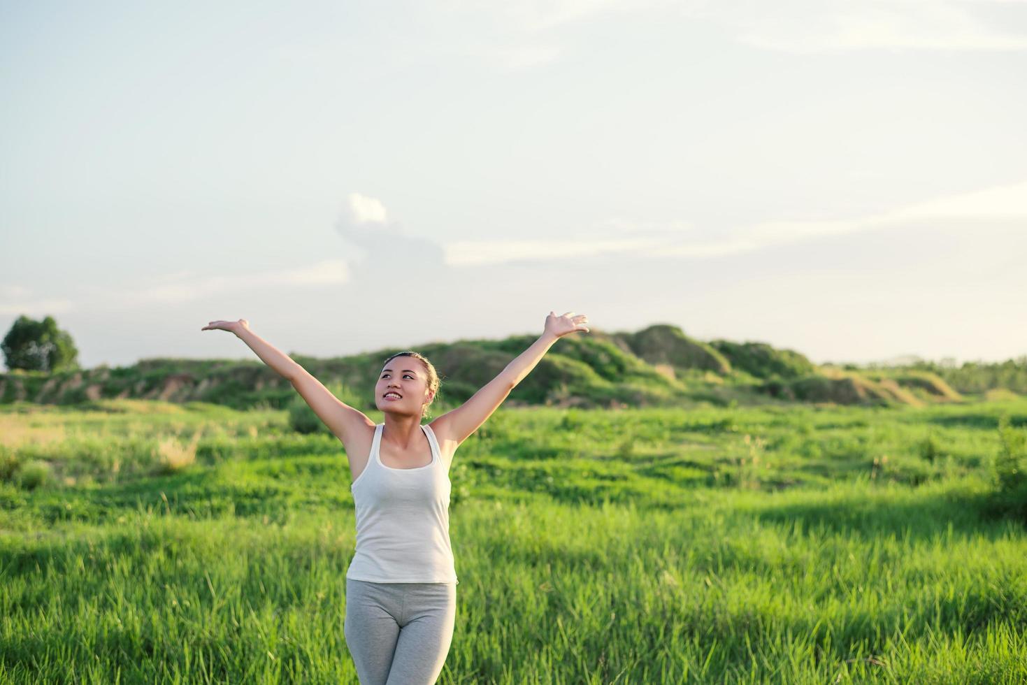 Feliz hermosa mujer con los brazos estirados en una pradera foto