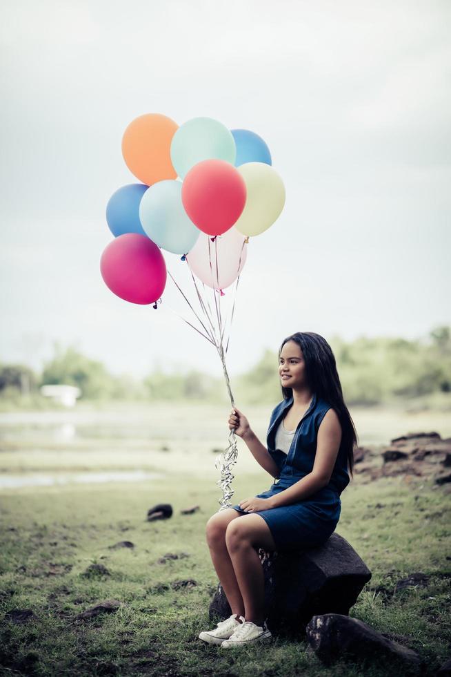 Young woman holding colorful balloons in nature photo