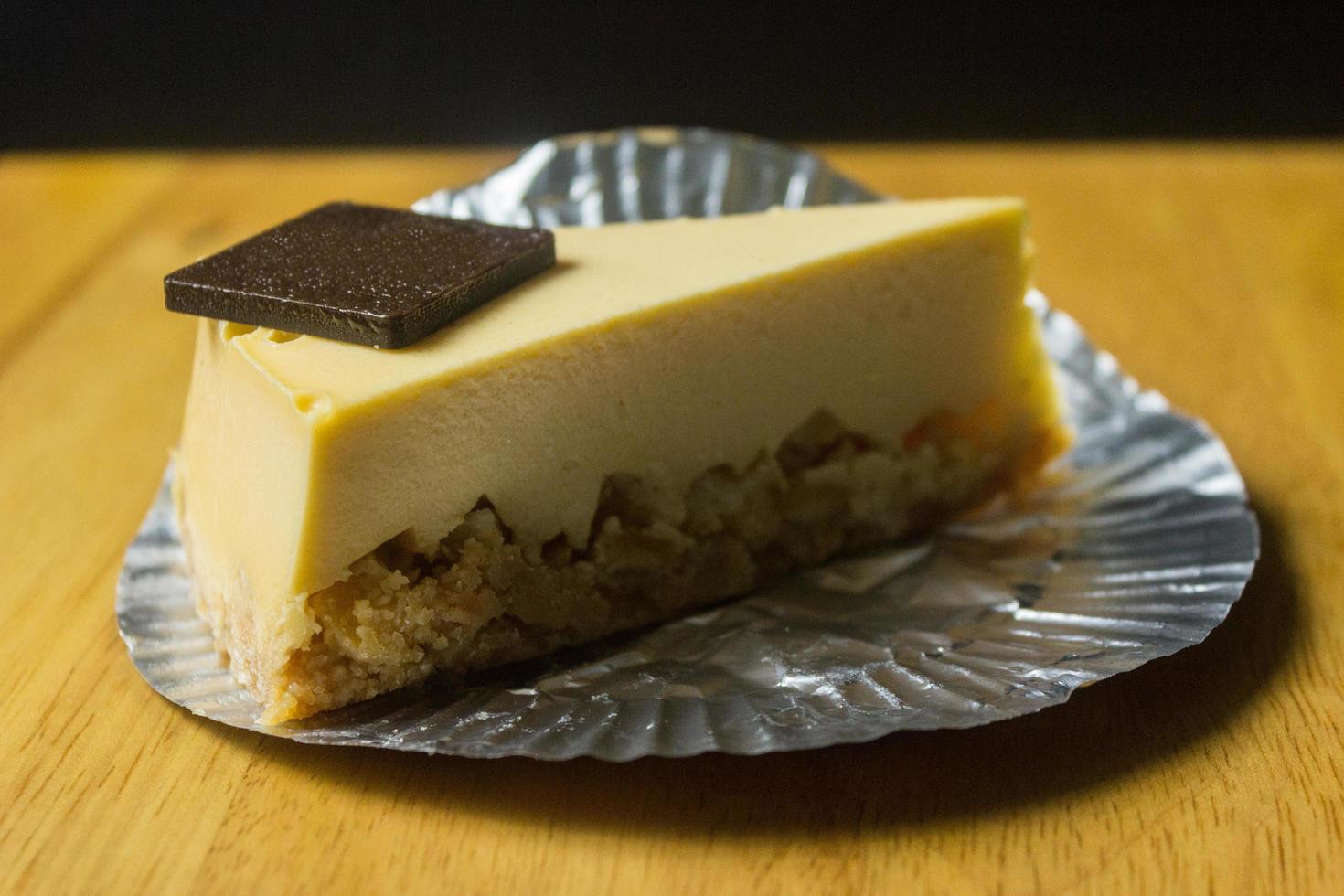 Rebanada de tarta de queso en la mesa de madera y fondo oscuro foto