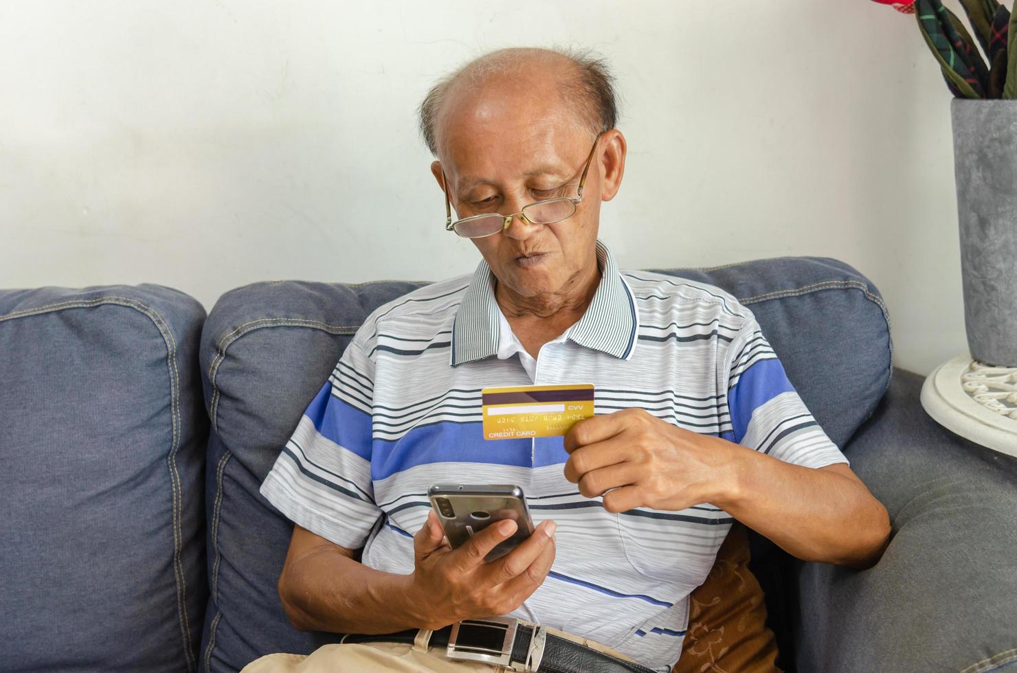 Old man using a credit card to buy something online photo