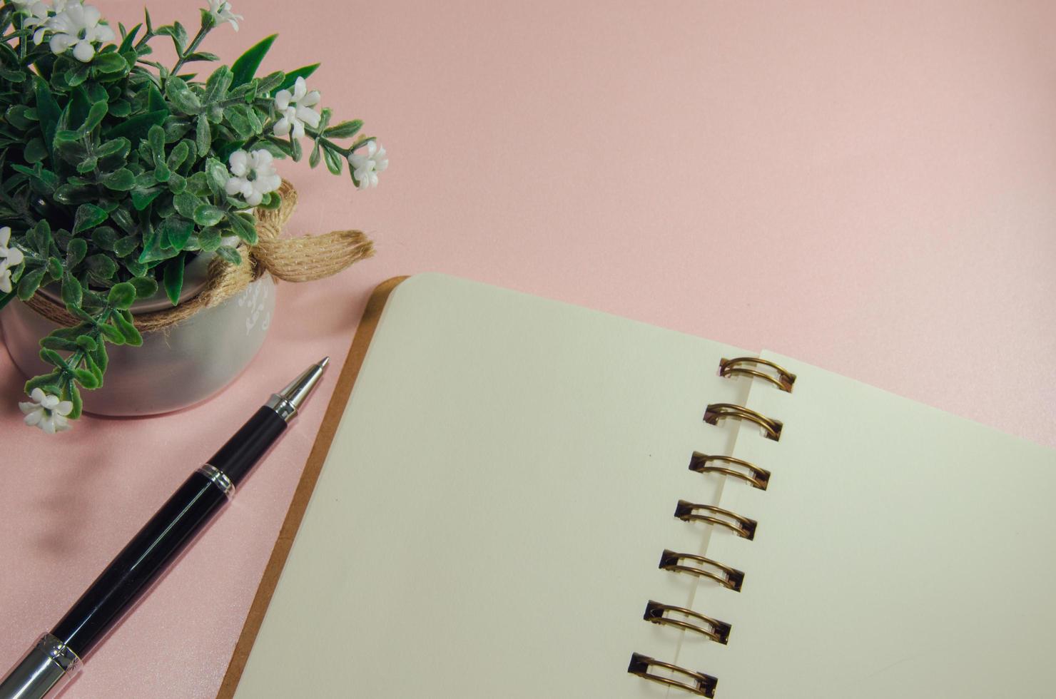 cuaderno y bolígrafo en escritorio rosa foto