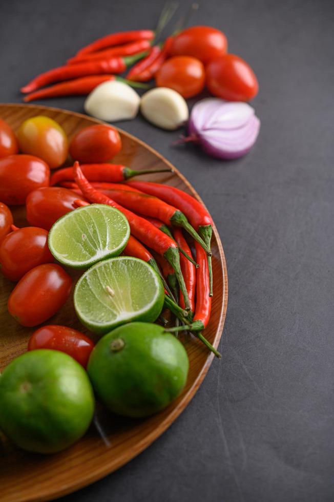 Lime slices, shallots, garlic, tomatoes, lettuce and peppers on a wooden plate photo