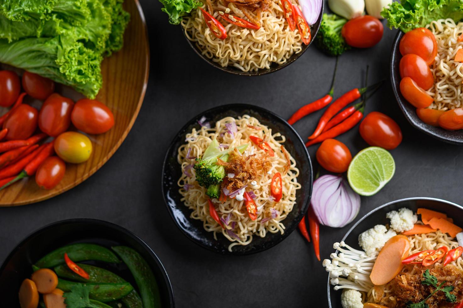 Noodles in a frying pan with ingredients on black cement background photo