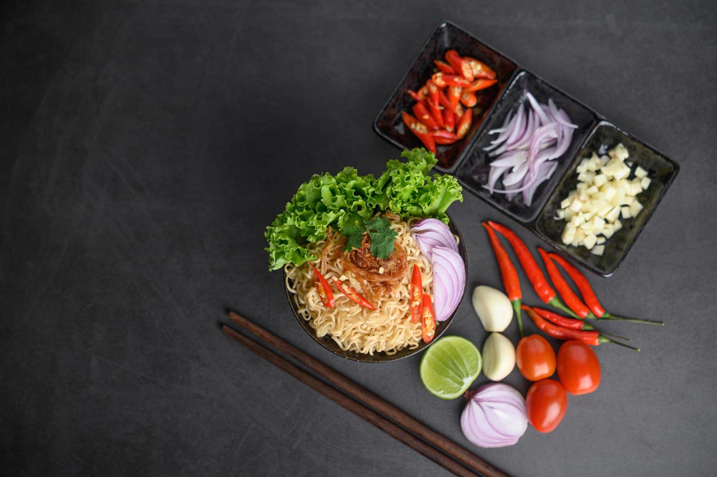 Bowls of noodles with ingredients and chopsticks photo