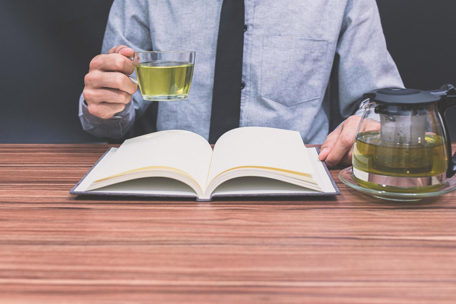 Person drinking tea while reading a book photo