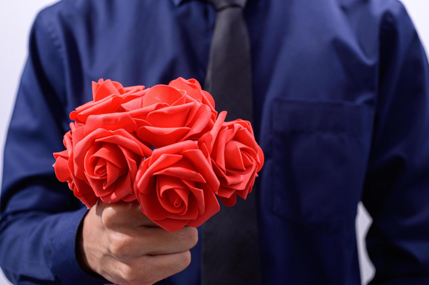 Man in blue suit holding red flowers photo