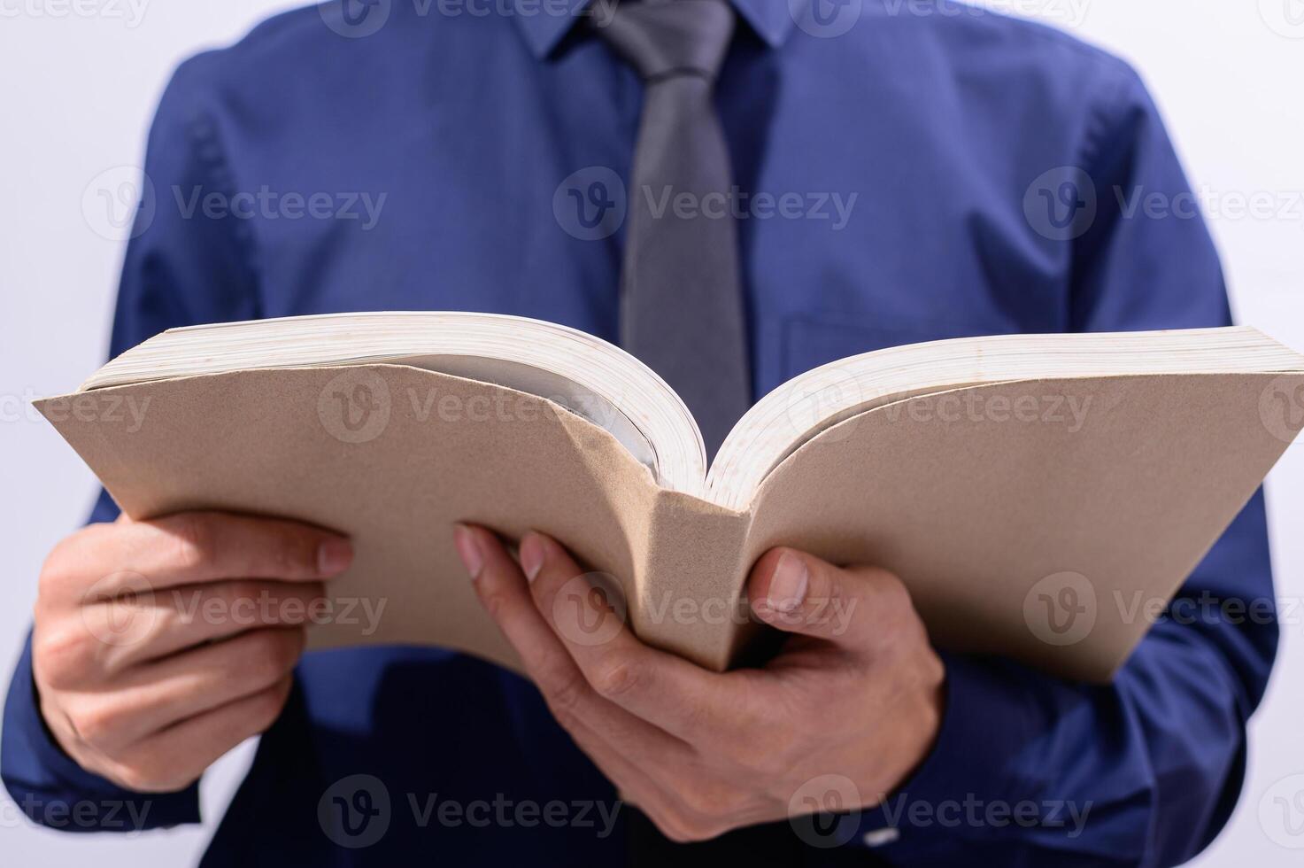 A man in a blue shirt and tie is holding an open book photo
