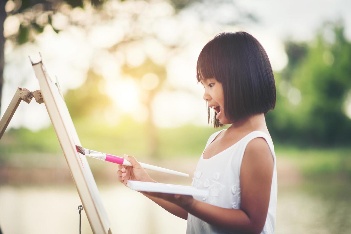 niña artista pintando un cuadro en el parque foto