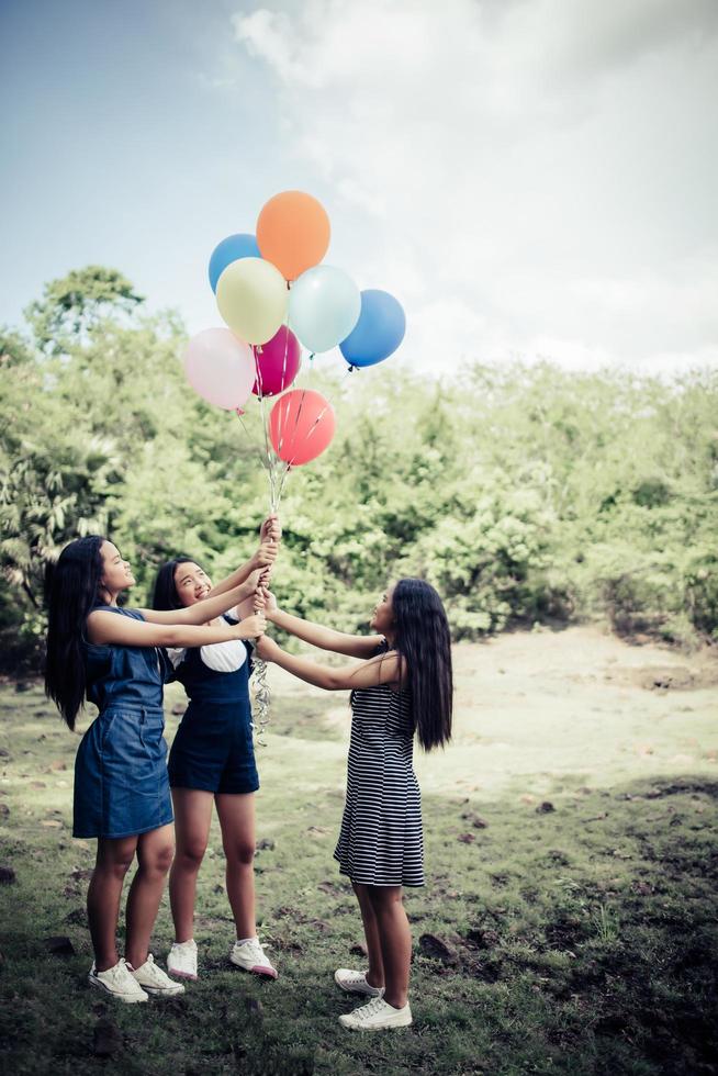 Grupo de novias felices sosteniendo globos multicolores en un parque foto