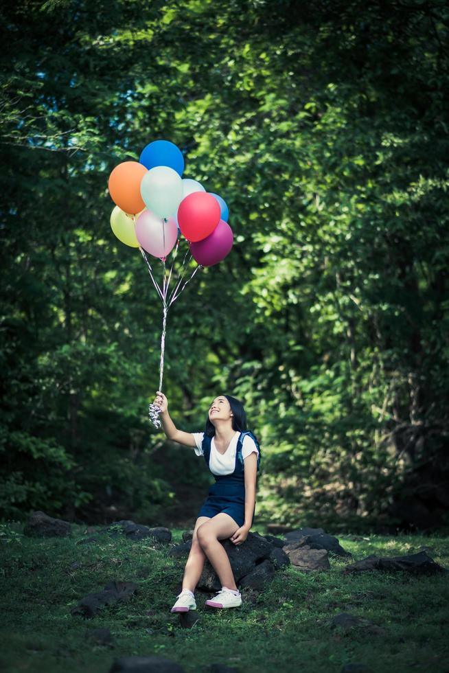 niña sosteniendo globos de colores en la naturaleza foto