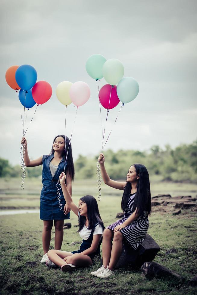 Happy group girlfriends holding multi-colored balloons at a park photo